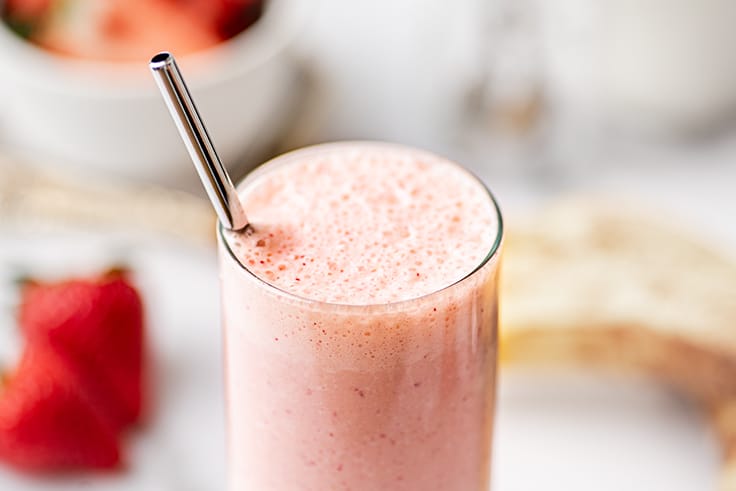 Close up photo of strawberry banana milkshake in a glass.