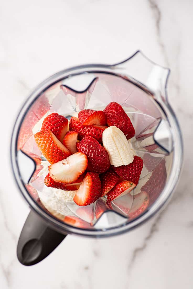 Overhead photo of strawberries, banana, and ice cream in a blender.