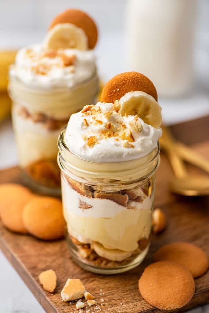 Banana pudding layered in a jar with whipped cream, bananas, and vanilla wafers.