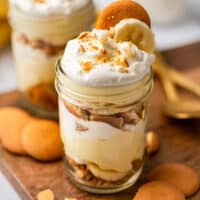 Banana pudding layered in a jar with whipped cream, bananas, and vanilla wafers.