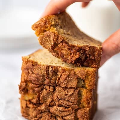 Hand picking up a small slice of banana bread.