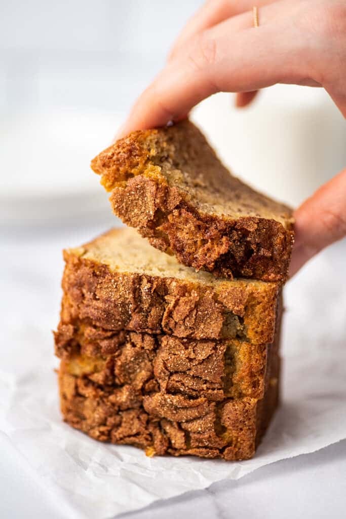 Hand picking up a small slice of banana bread.