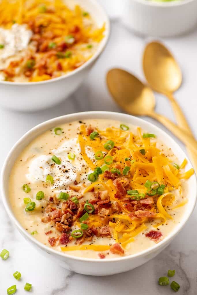 Bacon potato soup topped with cheese and bacon in a white bowl.