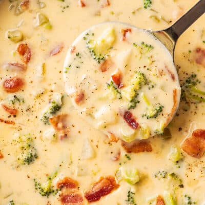 A ladle scooping out cheesy broccoli potato soup.