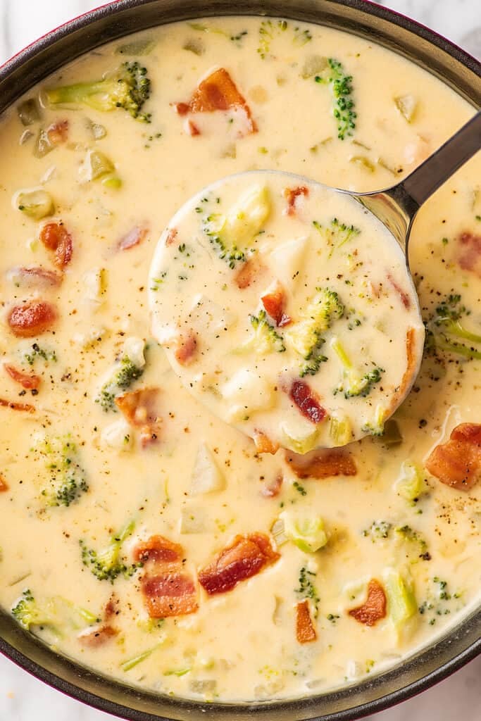 A ladle scooping out cheesy broccoli potato soup.