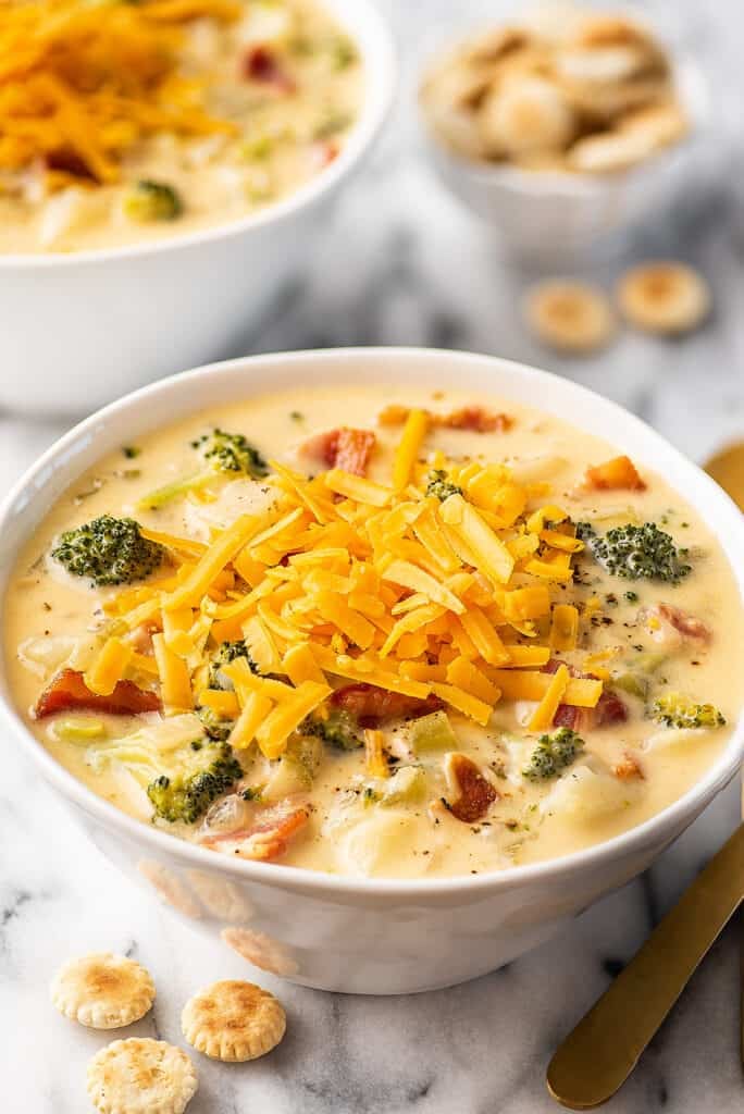 Broccoli potato soup in a white bowl with cheese on top.