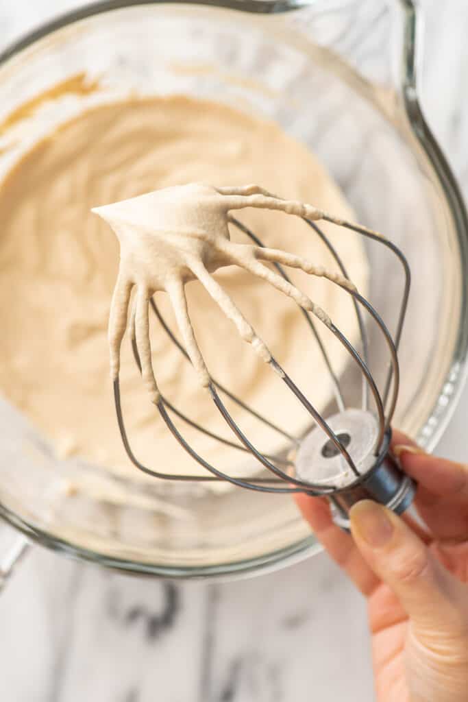 Hand holding a stand mixer mix with coffee whipped cream on it.
