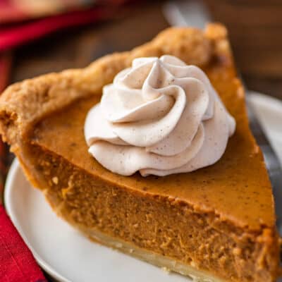 Cinnamon whipped cream on a slice of pumpkin pie.