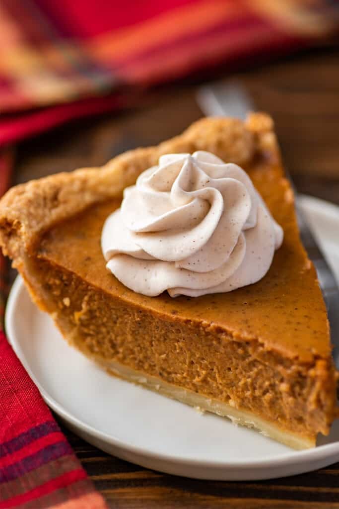 Cinnamon whipped cream on a slice of pumpkin pie.