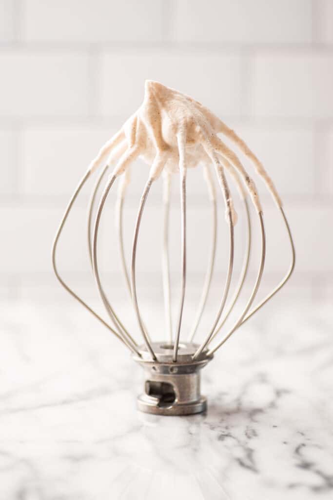 Cinnamon whipped cream on a whisk attachment on the counter.