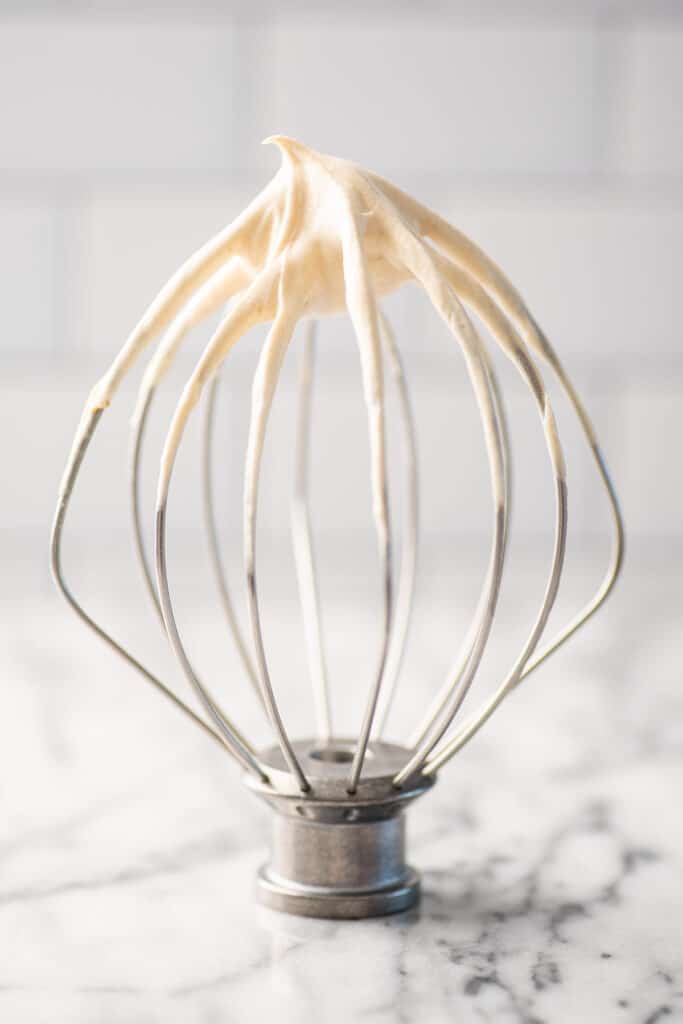 Peanut butter whipped cream on a stand mixer whisk on the counter.