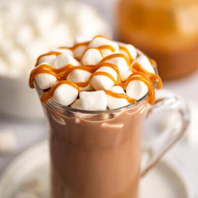 Salted caramel hot chocolate in a mug with marshmallows and caramel drizzle.