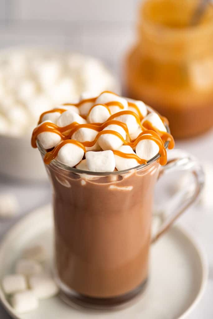 Salted caramel hot chocolate in a mug with marshmallows and caramel drizzle.