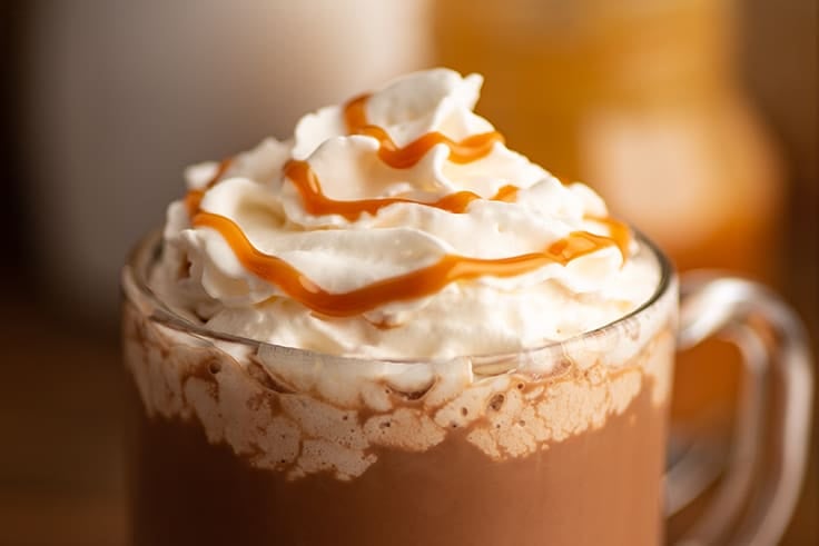 Close photo of salted caramel mocha in a glass mug with whipped cream.