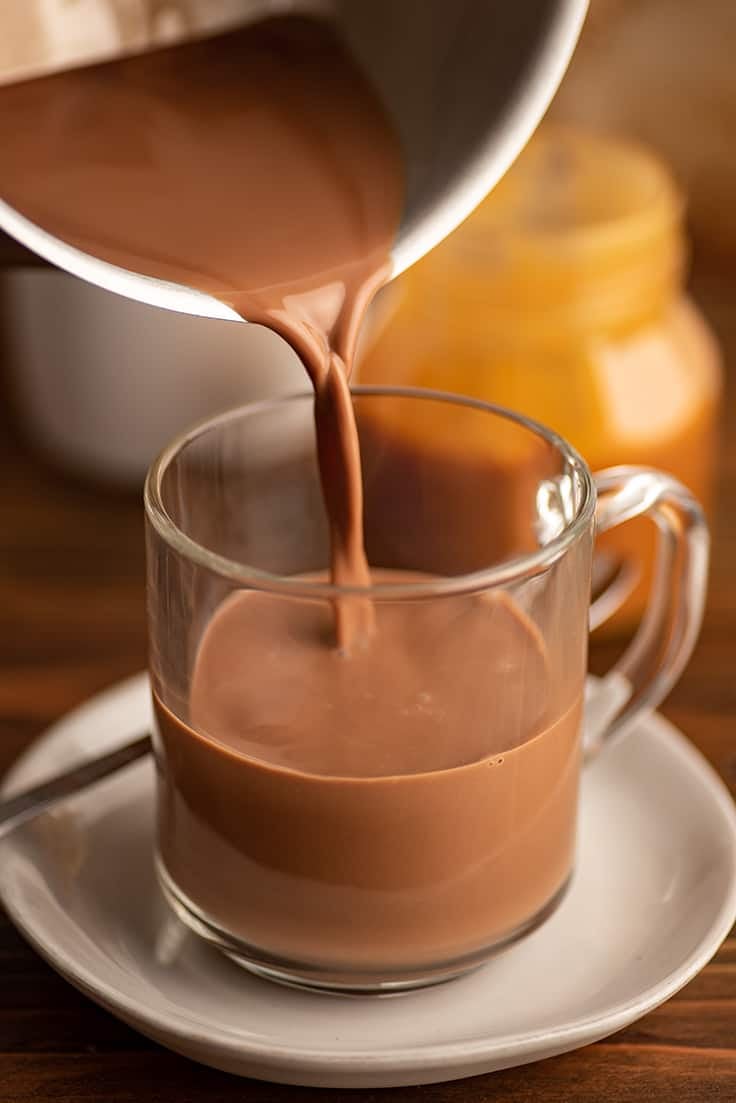 Salted caramel mocha being poured into a glass mug.