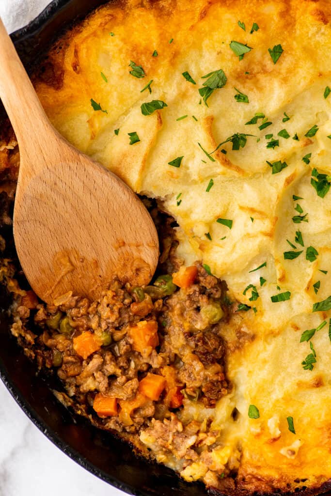 Cottage pie with ground beef filling in a cast iron pan.