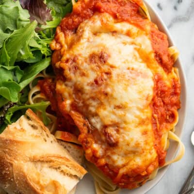 A chicken breast with mozzarella baked on top on a plate