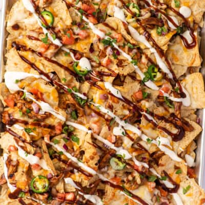 BBQ chicken nachos with ranch and bbq sauce drizzled on.