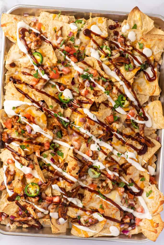 BBQ chicken nachos with ranch and bbq sauce drizzled on.