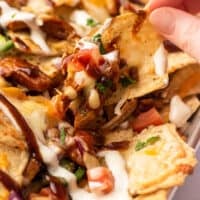 BBQ chicken nachos being picked up from a sheet pan.