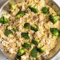 Chicken and orzo with broccoli in a skillet.