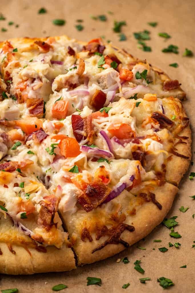 Bacon chicken ranch pizza on parchment paper.