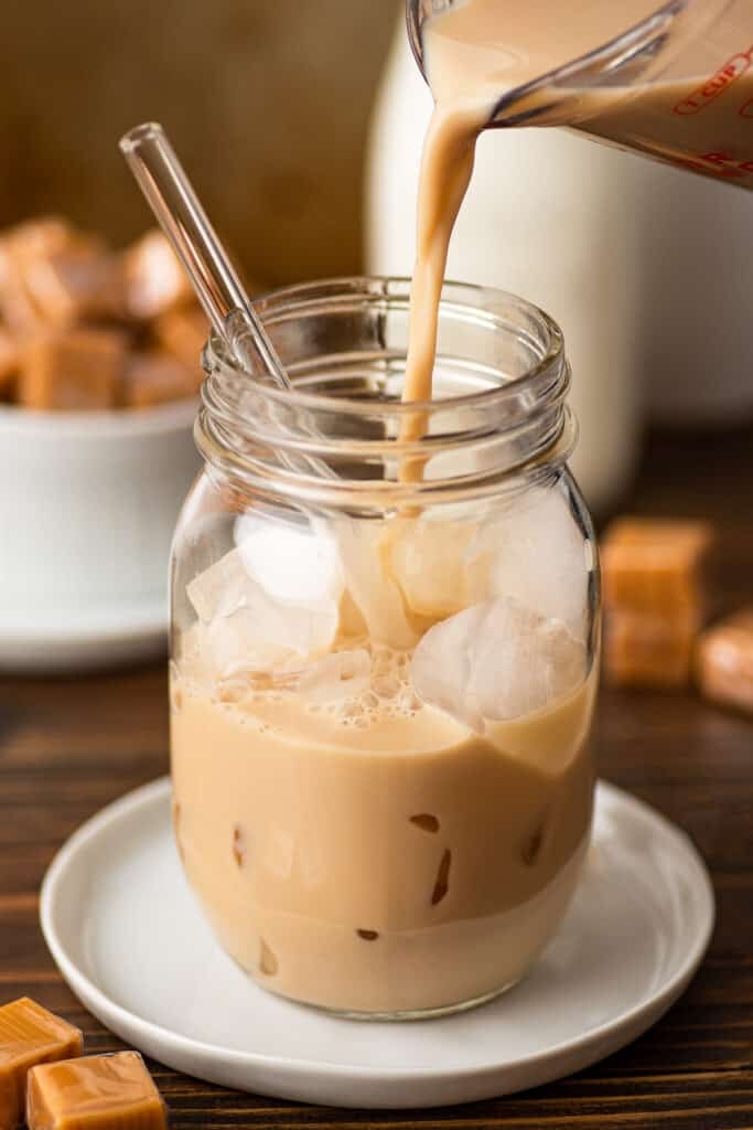 Caramel coffee being poured over ice.