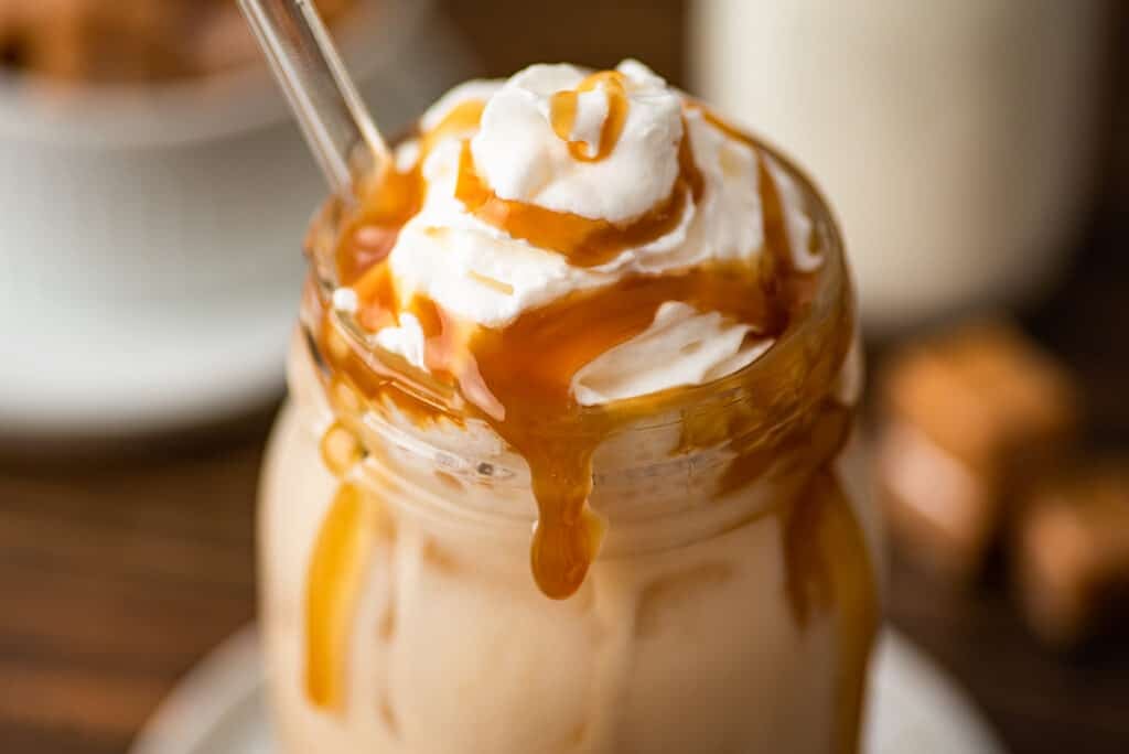 Close photo of iced caramel latte with whipped cream.