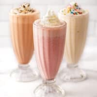 Strawberry, vanilla, and chocolate milkshake recipes in clear glasses.