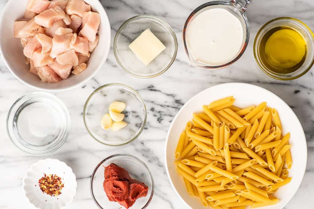 Ingredients for penne alla vodka with chicken on a counter.