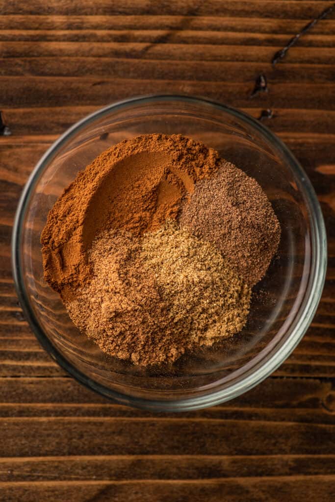 Ingredients for apple pie spice in a glass bowl.