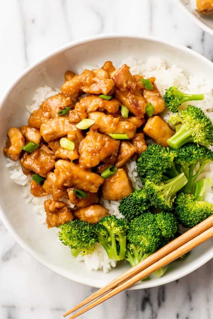 Bowl of rice with honey ginger chicken and broccoli on top.