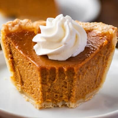Small pumpkin pie slice with a bite taken out of it.