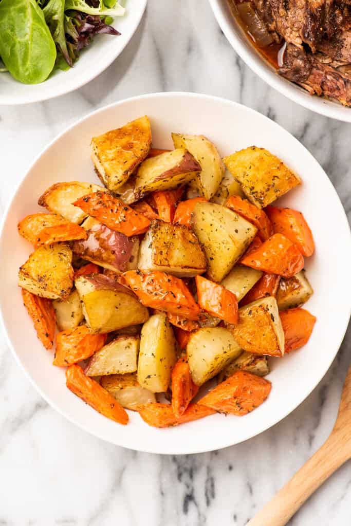Roasted carrots and potatoes in a bowl on a table.