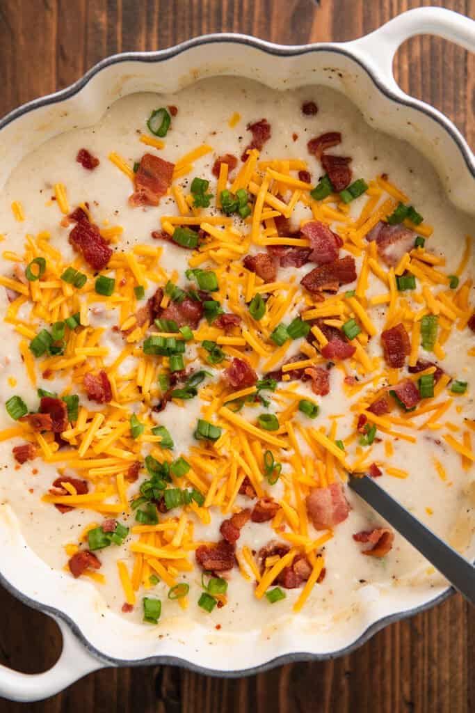 Close up photo of baked potato soup in a pot with a ladle.