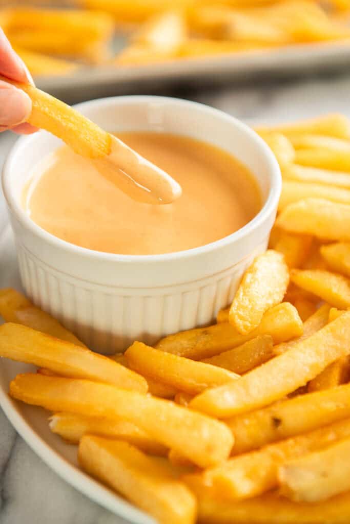 Fry being dipped in Sriracha aioli