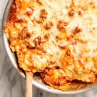 a baking dish of ravioli with a large wooden spoon