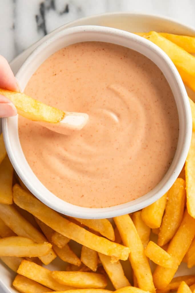 Close up of fry being dipped into sauce.