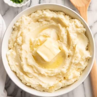 a bowl of sour cream mashed potatoes with a slice of butter on the top
