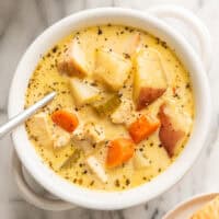 Creamy chicken and potato soup in a white bowl.